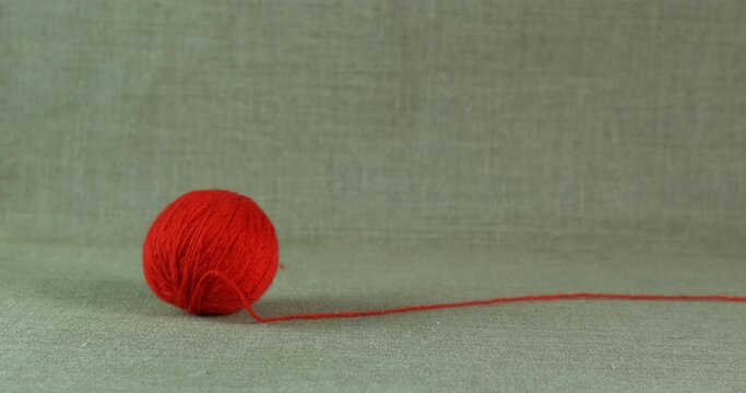 Red wool thread on the floor. A red woolen yarn roll on the floor.