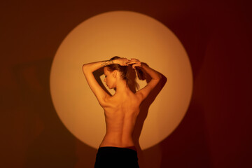 Beautiful girl posing in an orange circle. Shooting topless