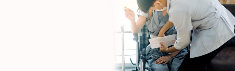 young asian physical therapist working with old man on working using a walker in hallway of nursing home