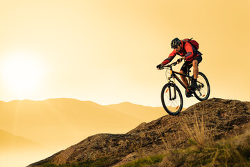 Cyclist Riding Bike on the Rocky Trail in the Summer Mountains at Sunset. Extreme Sport and Enduro Cycling Concept.