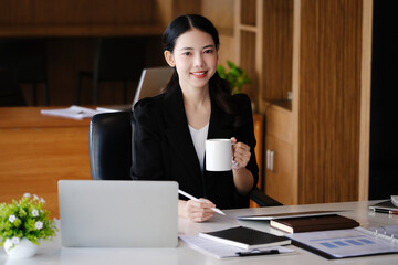 Company employees are sitting at work using computers, tablets and documents in their work.