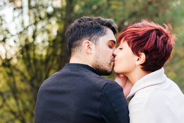 Newlywed couple giving an affectionate kiss outdoors in nature.
