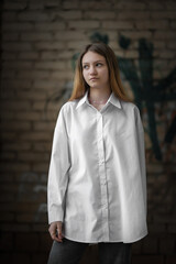 Portrait of a beautiful young girl in a light shirt on a dark background.