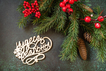 Holiday concept, merry Christmas card. Flat lay with fir tree branch and Christmas decorations with an inscription stating that miracles are real on a dark green stone background.