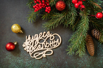 Holiday concept, merry Christmas card. Flat lay with fir tree branch and Christmas decorations with an inscription stating that miracles are real on a dark green stone background.