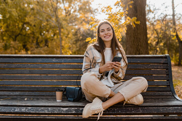 attractive young woman walking in autumn wearing jacket using phone