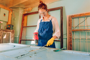 Young woman wearing protective glasses and apron working in the workshop