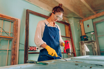 Young woman wearing protective glasses and apron working in the workshop