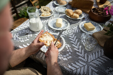A man while spreading butter on a roll. A country breakfast.