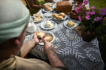 A man while spreading butter on a roll. A country breakfast.