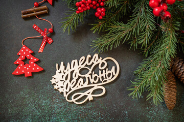 Holiday concept, merry Christmas card. Flat lay with fir tree branch and Christmas decorations with an inscription stating that miracles are real on a dark green stone background.