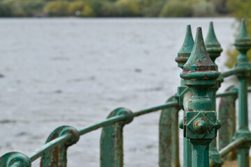 Green metal bridge railings in front of a lake