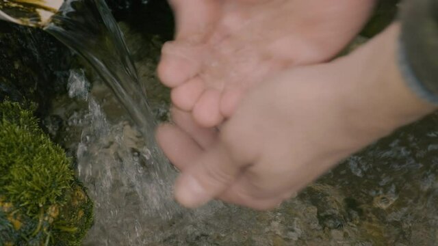 Forest spring. Men's hands collect water in the palm of their hands. Lifestyle concept, local travel.