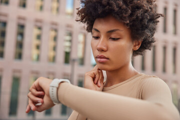 Healthy lifestyle concept. Curly haired woman checks pulse after jogging workout touches neck looks...
