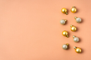 Gold glittering balls on a Christmas tree are laid out in a row on a beige background. Christmas decorations.  Copy space