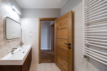 Modern interior of bathroom. Wooden door with tile floor. Dryer.