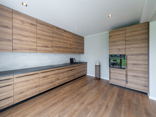 Interior of modern wooden kitchen with built-in appliances in house.