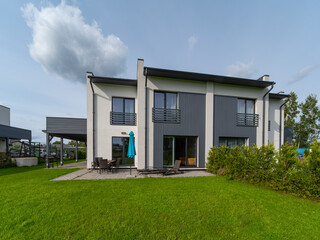 Modern exterior of luxury private house. Garden with green lawn.