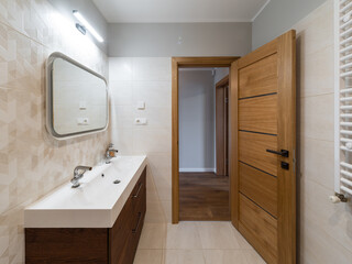 Modern interior of bathroom. White sink. Wooden door with tile floor.