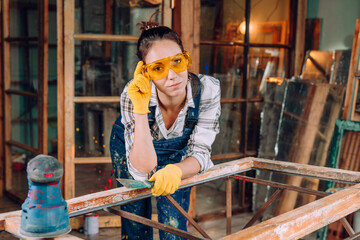 Young woman wearing protective glasses working in the workshop