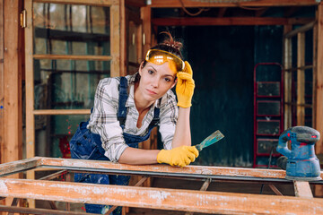 Young woman wearing protective glasses working in the workshop