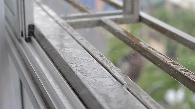 El clima lluvioso a trav&eacute;s de la ventana cae gotas cerca. Mal tiempo fuera. Capturando gotas de lluvia cayendo dentro del apartamento por la ventana