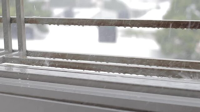 El clima lluvioso a trav&eacute;s de la ventana cae gotas cerca. Mal tiempo fuera. Capturando gotas de lluvia cayendo dentro del apartamento por la ventana