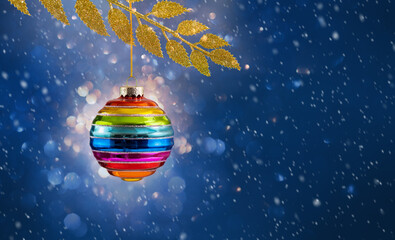 Christmas ball rainbow colors hanging on golden branch over blue. background. Christmas bauble in...