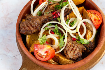 lamb ribs with baked potatoes and fresh onions, sprinkled with pomegranate on a marble background