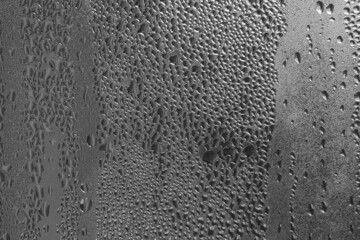 Raindrops on the window pane on a gray background. Natural pattern of raindrops. Texture for creativity. Water on the surface of the glass.
