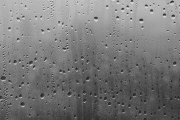 Raindrops on the window pane on a gray background. Natural pattern of raindrops. Texture for creativity. Water on the surface of the glass.