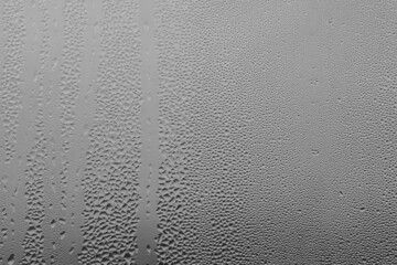 Raindrops on the window pane on a gray background. Natural pattern of raindrops. Texture for creativity. Water on the surface of the glass.