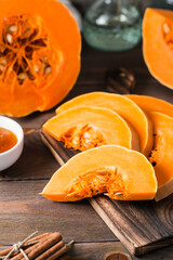 Pieces with ripe pumpkin seeds on a cutting board on a wooden table. Vegetarian food. Rustic style. Vertical view. Close-up
