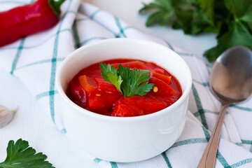 lecso national dish of Hungarian cuisine with pepper and tomato, greens on the white plate. lecho of tomatoes and sweet paprika with ingredients on the table. Hungarian food. copy space.