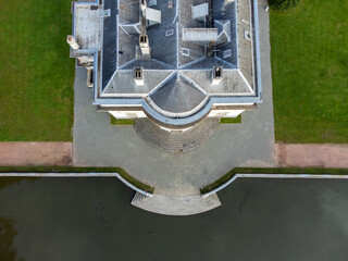 Top down view of Edegem Hof ter Linde castle by a pond surrounded by green grass in Belgium. Drone aerial shot