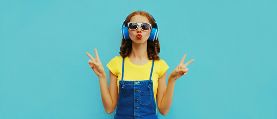 Portrait of cool girl with headphones listening to music on a colorful blue background