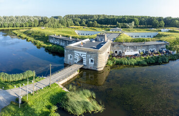 Top view of fortress Liezele, a concrete fort building from the war surrounded by a moat of water in summer with green grass and trees around. Drone aerial