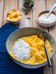 Corn porridge with cheese and sour cream sauce in a gray plate on a wooden background. Georgian cuisine.