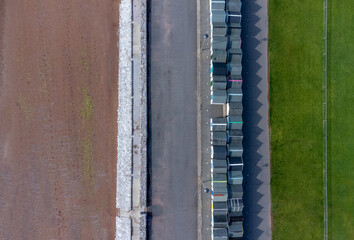 Top view of Paignton beach huts and road between green grass and trees. Drone aerial top down view photo.