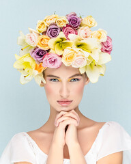 Head portrait of a young model in studio with flowers instead of hairstyles on a tender pastel background