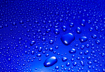 Abstract background - water drops on a blue shiny surface.