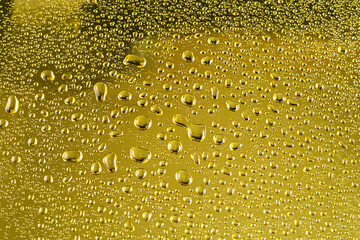 Abstract background - water drops on a golden shiny surface.