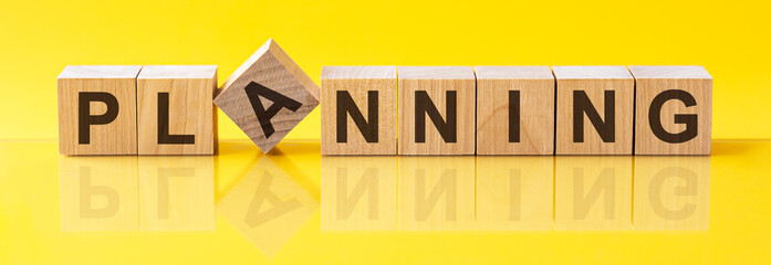 planning word is made of wooden building blocks lying on the yellow table, concept