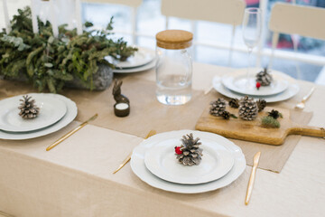 Christmas festive table setting of a festive dinner. Pine cone on a white plate