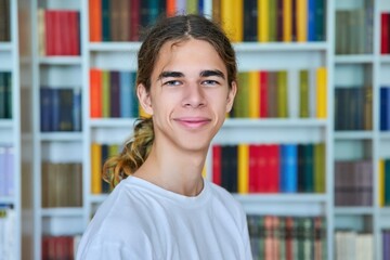 Portrait of a smiling teenage boy looking at the camera in the library.