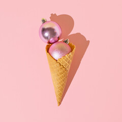 Ice cream cone with shiny pink Christmas baubles. Minimal xmas candy concept.