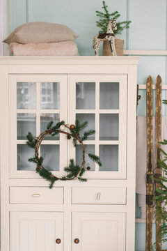 White wardrobe with a Christmas wreath, skis and decor in the living room of the house