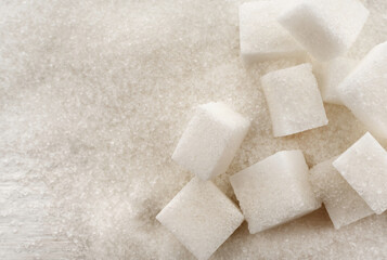 Refined sugar cubes are scattered over loose sugar. Sucrose ingredient for confectionery