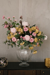 A luxurious bouquet of flowers in a glass transparent vase in the interior decor of the house