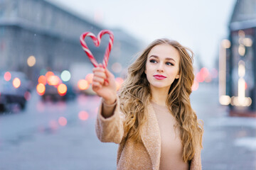 A sweet dreamy girl, a young woman holding a lollipop in the form of a heart on a winter day. The...